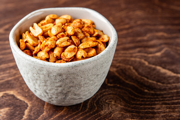 Roasted peanuts and salt in a bowl on a wooden background