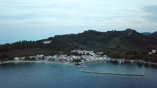 Limenas or Thassos City is the main city in Thassos Island , Greece , north-eastern Europe , aerial drone footage at sunset , showing the city , the harbor and the hills surrounding it.