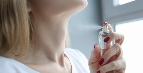 Woman sprinkling perfume on her neck closeup. Sale of perfumery concept