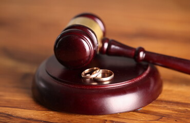 Closeup of judge hammer and wedding rings. Divorce proceedings concept