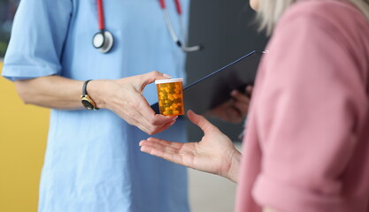 Doctor giving jar of pills to patient closeup. Pharmaceutical business concept