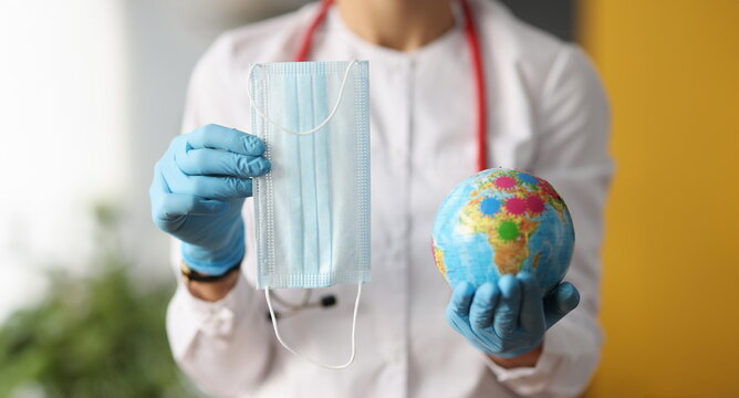 Doctor holding protective mask and globe closeup. Global global coronavirus pandemic concept
