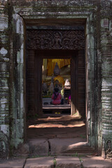 Woman praying inside a Buddhist temple with the door as a frame and Buddha in the center