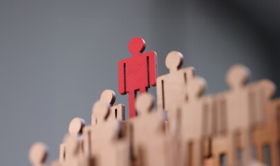 Red wooden figurine standing above others closeup. Leadership skills concept