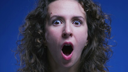 Woman reacting with shock and surprise, close-up face of an amazed female person in 20s feeling...