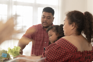 Asian family cooking together at kitchen. The chubby father and mother with girl feel happy in our morning breakfast in a weekend. cooking salad and vegetables.