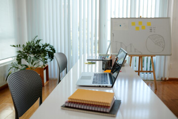 Desk with laptop and notebooks in spacious office of