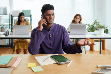 Indian entrepreneur in purple kurta talking on phone with colleague from another department