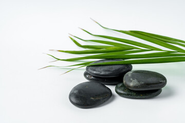 Obraz na płótnie Canvas Black spa pebbles with leaves isolated on white background