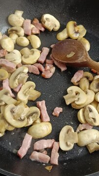 champignons de Paris et lardons de porc en cuisson dans une po&ecirc;le