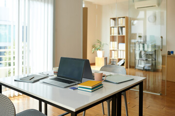 Desks with laptops, documents and planners in office of small company
