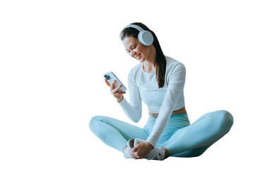 Cheerful brunette American girl in sportswear, headphones sitting on floor against transparent...