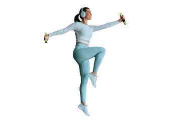 Active brunette American girl in sportswear jumps against transparent background holds dumbbells, at morning workout indoors enjoys music uses headphones. Gym, fitness healthcare.