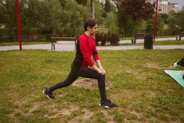 Sportsman does lunges to prepare legs for running long range in morning park. Male athlete does sports outdoors to maintain health