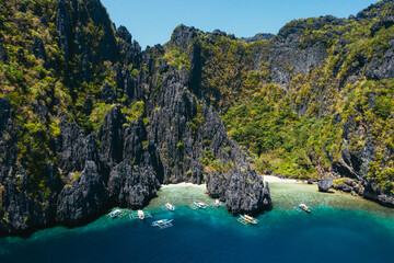Small lagoon in El nido. People walking on the white sand, with tropical jungle in the background....