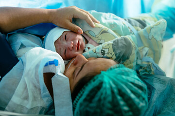 Newborn baby with mother in hospital, seconds after birth. Infant in maternity hospital