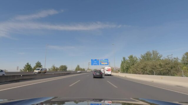 First person view, FPV, from dashcam of car driving towards Madrid from Granada in Andalusia, Sierra Nevada Mountains, Spain, Europe. Road trip video in POV, with bright, sunny, blue sky