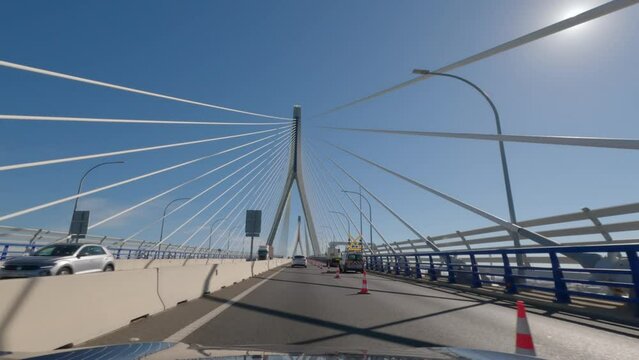 First person view, FPV, from dashcam of car driving across the Constitution of 1812 Bridge, La Pepa, in C&aacute;diz, Andalusia, Spain, Europe. Road trip video in POV, with bright, sunny, clear blue sky