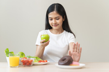 Obraz na płótnie Canvas Woman on dieting for good health concept. Close up female using hand push out her favourite donut and choose green apple and vegetables for good health.