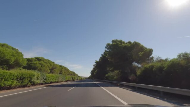 First person view, FPV, from dashcam of car driving in the beautiful Spanish countryside towards Seville, Andalusia, Spain, Europe. Road trip video in POV, with bright, sunny, blue sky