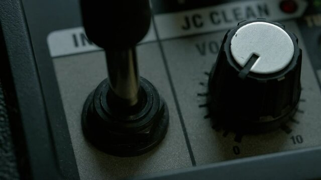 Man plug in jack and tuning volume knob on guitar amplifier. 4k video footage UHD 3840x2160