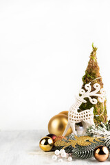 On a light background with space for writing text there is a small Christmas tree, a deer and New Year's decor.