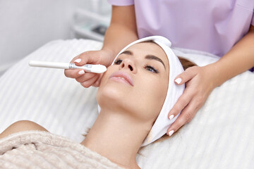 female hand touching the patient's face with a brush. beautician applies the mask to female face. facial skin care.
