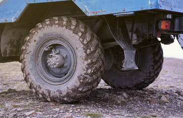Wheel closeup in a countryside landscape with a mud road. Off-road 4x4 suv automobile with ditry...