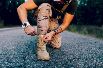 Crop anonymous Mature male commando tying shoelace while kneeling on road