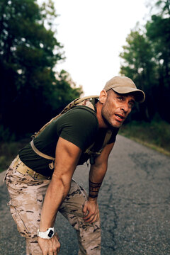 Exhausted middle aged military commando resting while standing on road