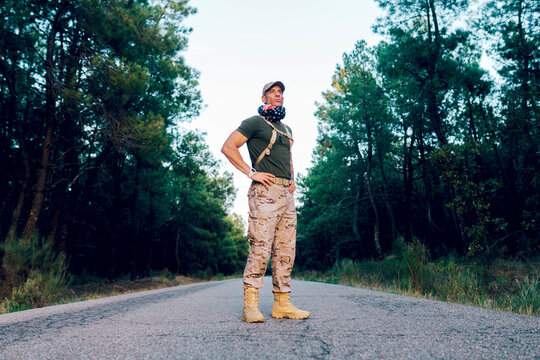 Low angle of Male commando with American flag wrapped around neck and looking away with pride while standing on road