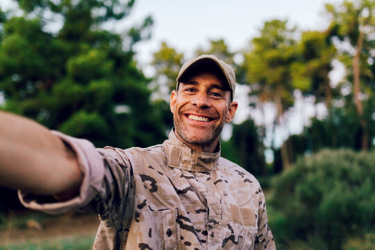 Happy middle aged ranger in uniform looking at camera while taking selfie