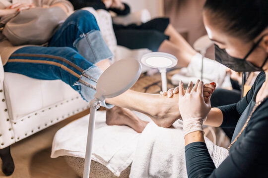 Crop masseuse massaging foot of customer during pedicure in beauty salon