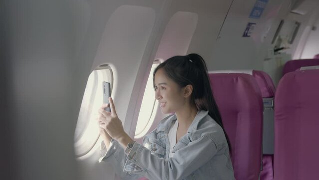 Excited female passenger traveler taking pictures at the window of the plane..