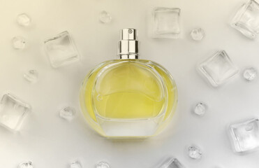 Female perfume yellow bottle, Objective photograph of perfume bottle in ice cubes and water on white table. View from above. Mockup product photo, concept of freshness and aroma