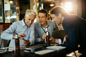 Businessmen having beer after work in bar or cafe