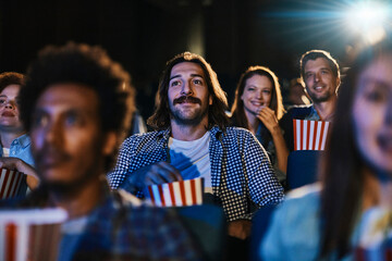 Smiling young man watching movie at the cinema