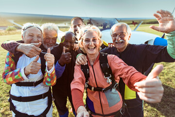 Group of joyful seniors take a selfie after their skydiving adventure