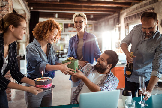 Young woman giving colleague birthday present at the office