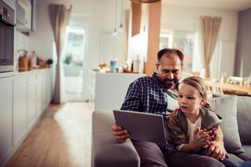 Father and daughter using tablet at home