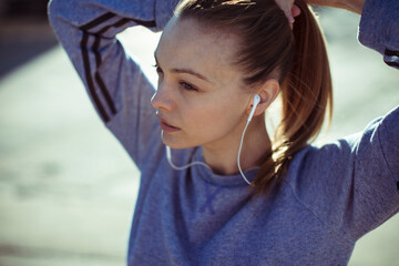 Young female runner tying ponytail before city jog