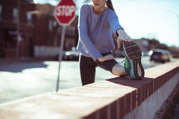 Young fit woman doing stretch exercise before city jog