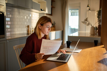 Focused young woman working from home on laptop
