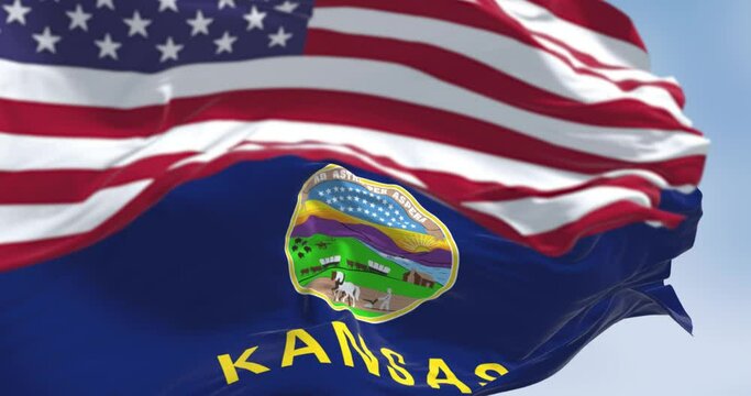 Kansas state flag and the American flag waving in the wind on a clear day