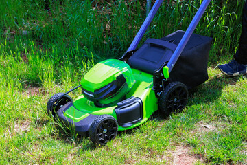 Fototapeta premium Mowing green grass using an electric lawn mower is gardener man