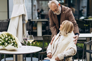 A romantic date of an elderly couple celebrating their anniversary in a cafe