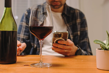 Man holding a phone and a glass of wine, using alcohol tracker app, mindful drinking.