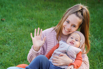 A girl and a little child are sitting on the grass with a crop of nird and apples