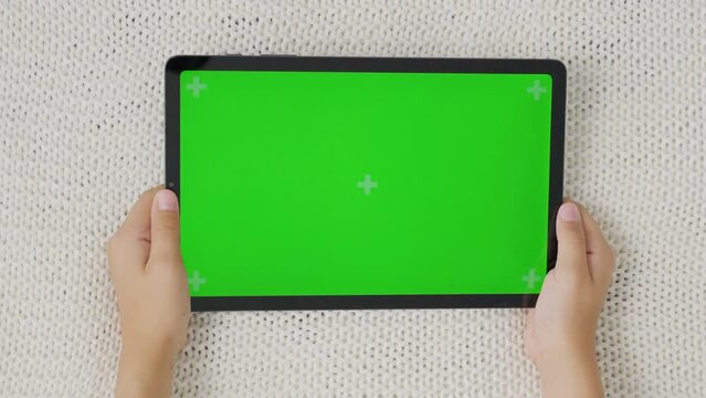 Close up kids hands holding, tapping on a tablet with green screen. Mock up