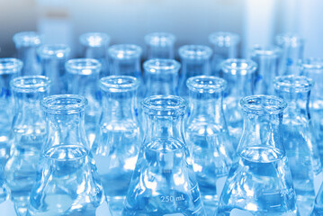 Glass flask with liquid in laboratory. Blue tone. Selective focus.